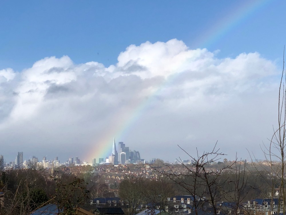 Picture of a London cityscape with blue sky, clouds and a big rainbow